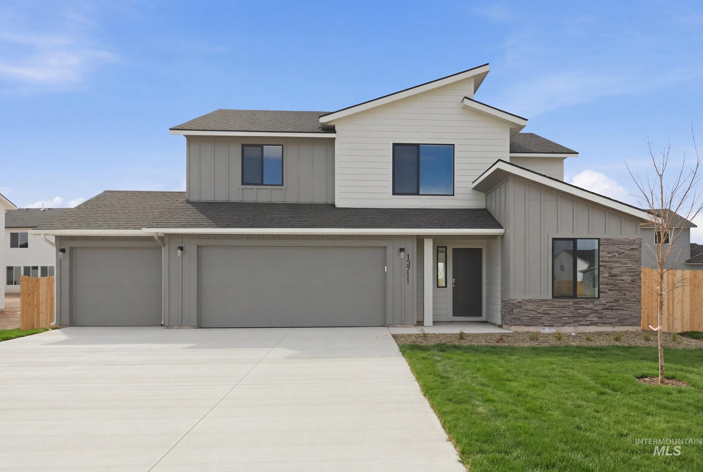 View of front of house with roof with shingles, board and batten siding, concrete driveway, and an attached garage