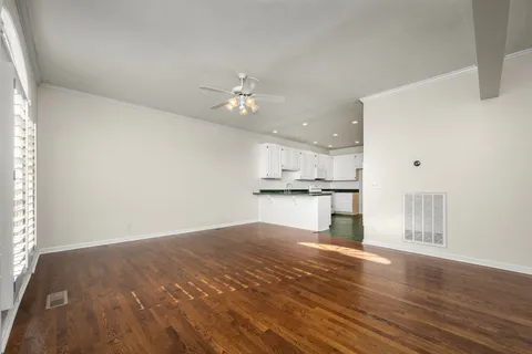 a view of kitchen and empty room with wooden floor