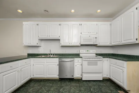 a kitchen with white cabinets white appliances sink and dishwasher