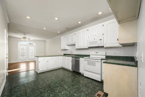 a large kitchen with stainless steel appliances granite countertop a stove a sink a refrigerator and white cabinets