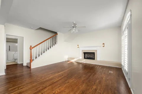 a view of an empty room with wooden floor fireplace and a window