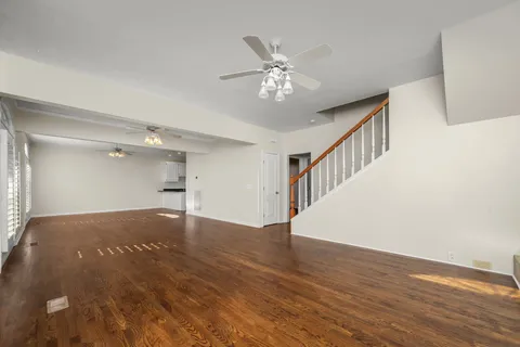a view of an empty room with wooden floor and a chandelier