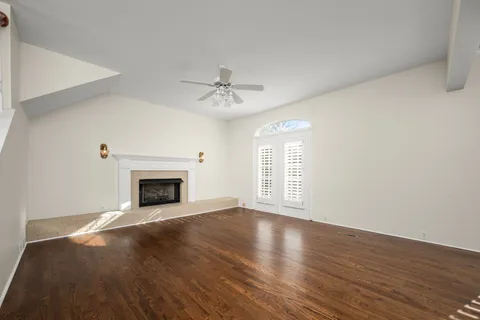 a view of an empty room with wooden floor and a fireplace