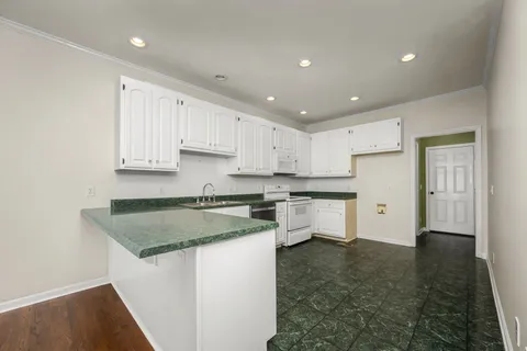 a kitchen that has a lot of white cabinets and stainless steel appliances