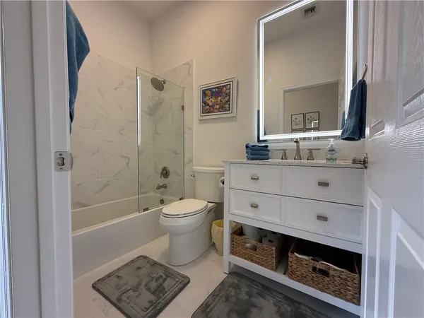 a bathroom with a double vanity sink a toilet a mirror and shower