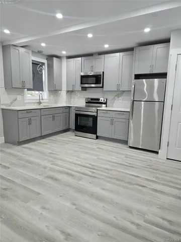 a large kitchen with a refrigerator a stove top oven a sink and cabinets