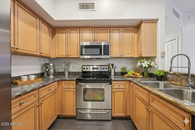 a kitchen with stainless steel appliances granite countertop a sink a stove and cabinets