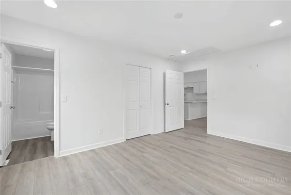 a view of an empty room with wooden floor and closet