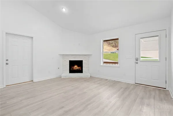 an empty room with wooden floor fireplace and windows