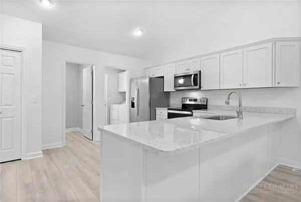 a kitchen with stainless steel appliances a refrigerator sink and white cabinets