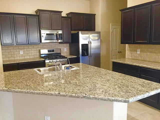 a kitchen with kitchen island granite countertop a sink stove and refrigerator