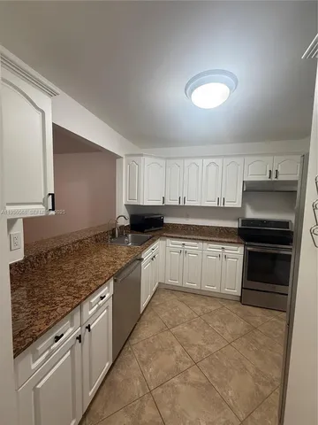 a kitchen with granite countertop a stove sink and cabinets