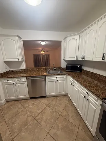 a large kitchen with granite countertop a sink a stove and cabinets