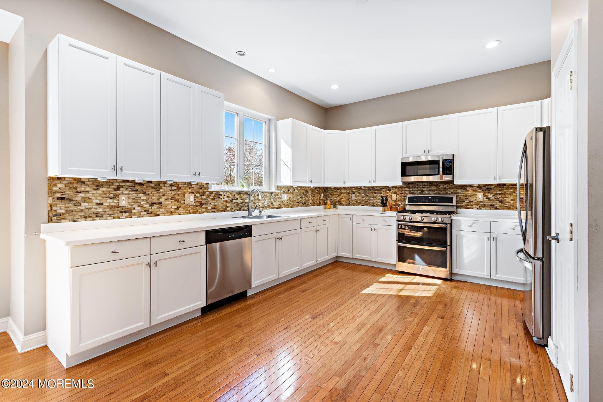25 Firestone Drive Howell, NJ 07731 - Photo 4 of 65 a kitchen with stainless steel appliances a microwave a stove a sink dishwasher and white cabinets with wooden floor