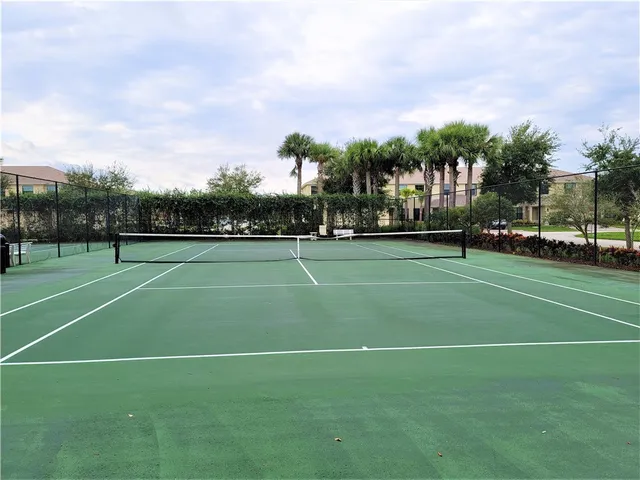a view of a tennis ground with large trees