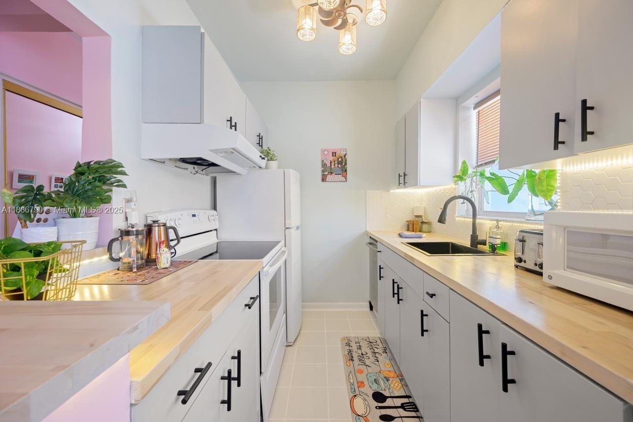 315 Van Buren Street, Unit 104B Hollywood, FL 33019 - Photo 7 of 22 a kitchen with sink a counter and appliances