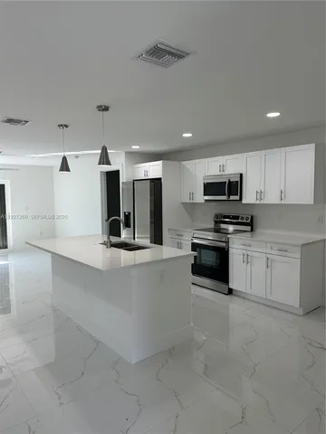 a kitchen with stainless steel appliances a refrigerator sink and stove top oven