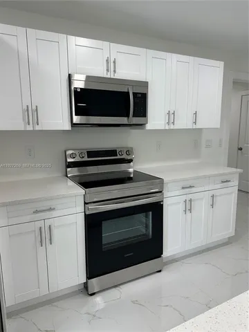 a kitchen with stainless steel appliances granite countertop grey cabinets a stove a sink and dishwasher