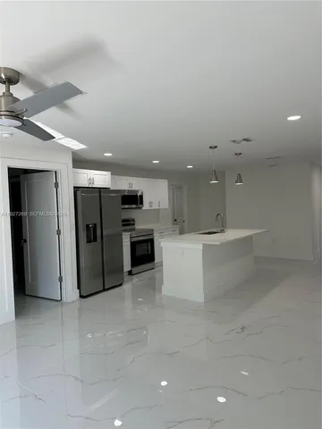 a kitchen with stainless steel appliances kitchen island granite countertop a refrigerator and a stove top oven