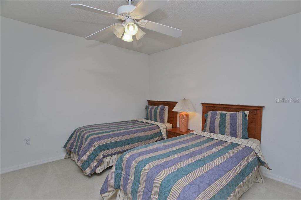 5270 Hyland Hills Avenue, Unit 1722 Sarasota, FL 34241 - Photo 25 of 30 a bedroom with a bed and a chandelier