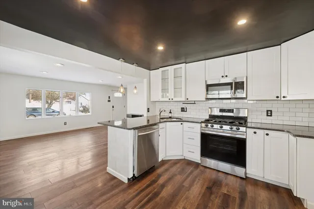 a kitchen with stainless steel appliances granite countertop a stove and white cabinets