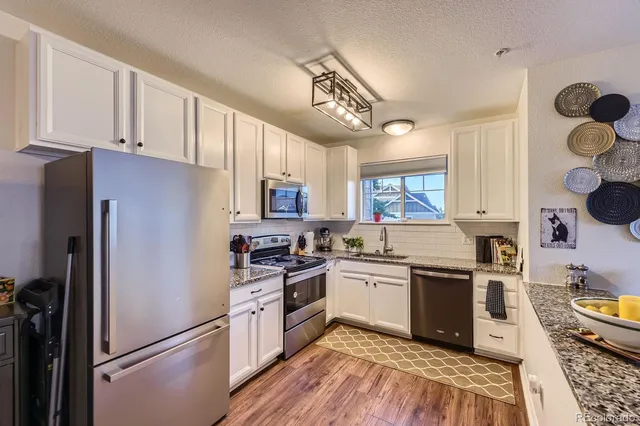 a kitchen with a refrigerator a sink and wooden floors