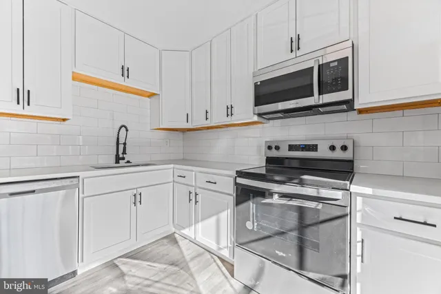 a kitchen with stainless steel appliances granite countertop grey cabinets a stove a microwave and a sink