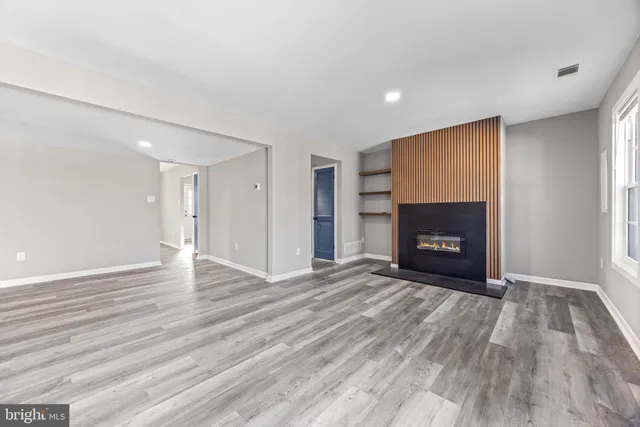 a view of empty room with wooden floor and fireplace