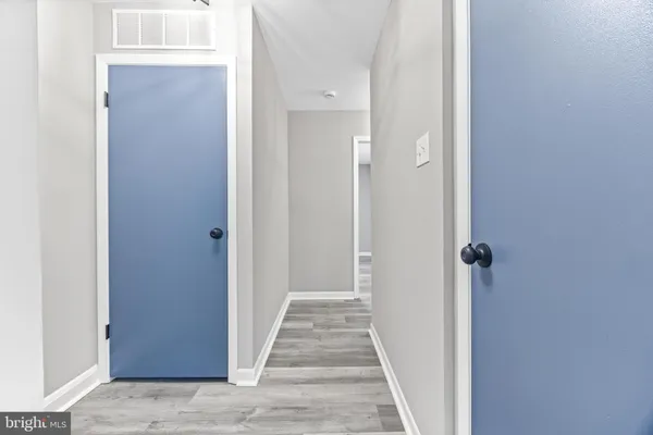 a view of a hallway with wooden floor and a bathroom