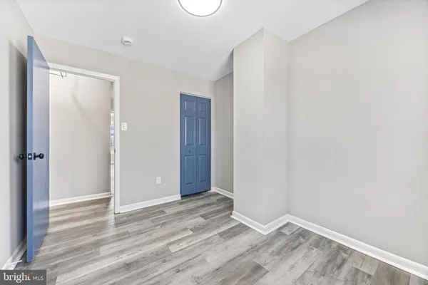 a view of an empty room with wooden floor and closet