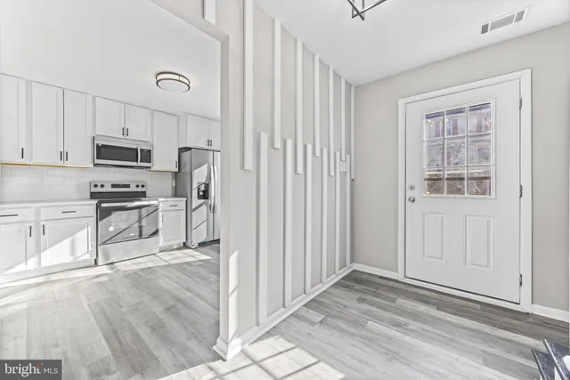 a kitchen with stainless steel appliances granite countertop a refrigerator sink and white cabinets