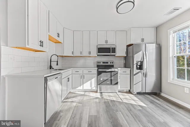 a kitchen with stainless steel appliances a refrigerator sink and cabinets