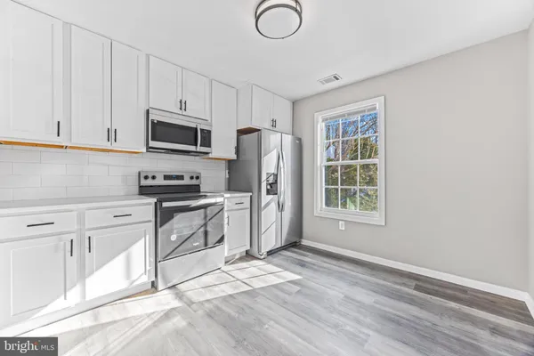a kitchen with a refrigerator stove and white cabinets