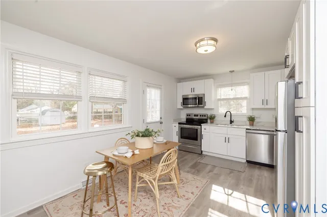 a kitchen with stainless steel appliances granite countertop a stove a sink a refrigerator with a dining table and chairs