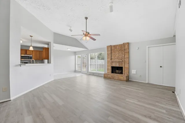 an empty room with wooden floor fireplace and windows