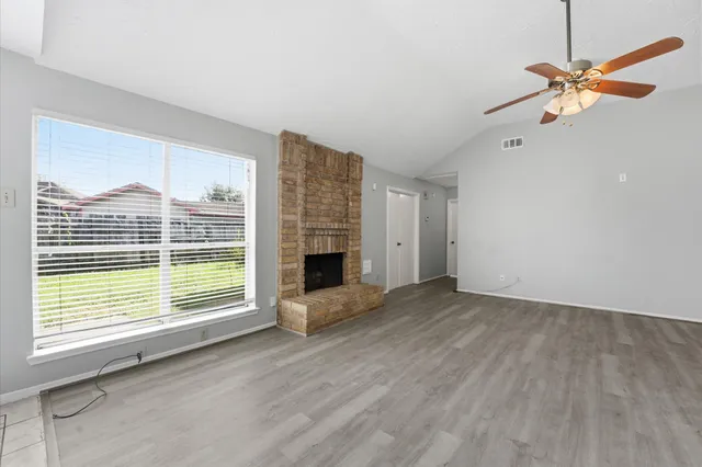 a view of an empty room with a window and wooden floor