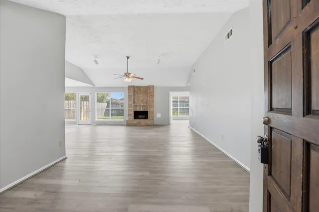 an empty room with wooden floor and a kitchen