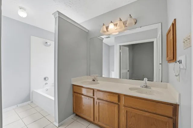 a bathroom with a double vanity sink mirror and bathtub