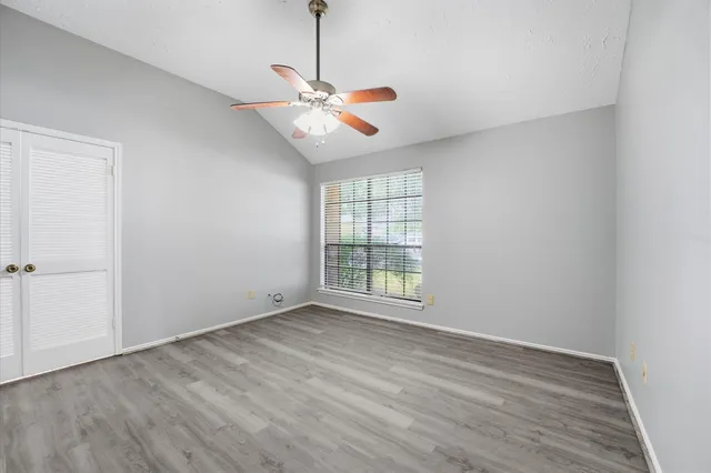 a view of an empty room with wooden floor and a window