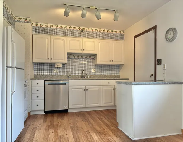 a kitchen with granite countertop white cabinets and white appliances