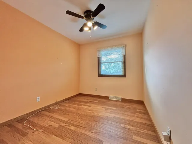 an empty room with a ceiling fan and wooden floor