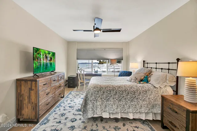 a bedroom with a large bed and a flat tv screen on dresser