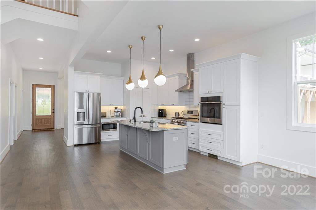 112 Meadow Breeze Road Arden, NC 28704 - Photo 9 of 44 a kitchen with stainless steel appliances kitchen island granite countertop a refrigerator oven a sink dishwasher and white cabinets with wooden floor