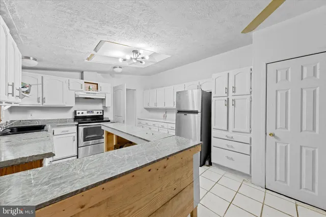 a kitchen with stainless steel appliances granite countertop a refrigerator and a stove top oven