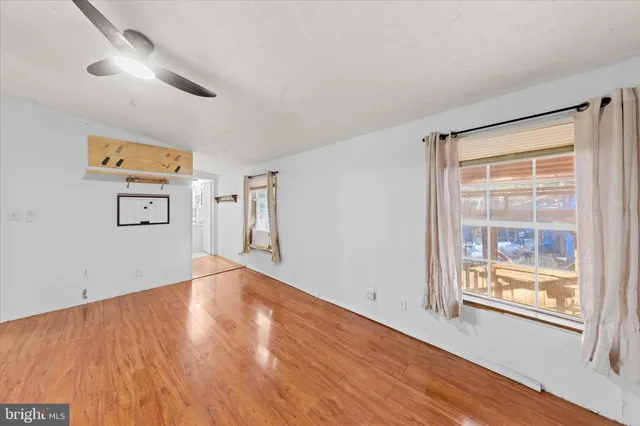 a view of empty room with wooden floor and fan