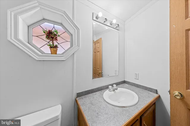 a bathroom with a granite countertop sink a toilet and mirror