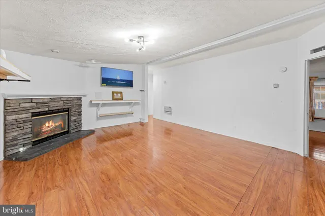 a view of kitchen and empty room with wooden floor