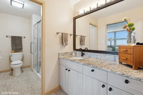 a bathroom with a granite countertop sink a toilet and a mirror