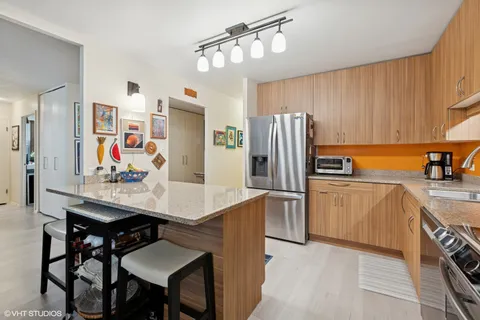 a kitchen with stainless steel appliances a refrigerator a sink a stove a dining table and chairs