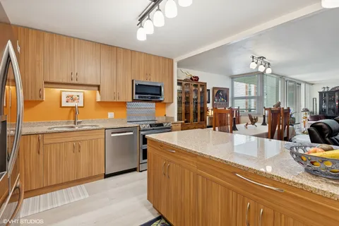 a large kitchen with kitchen island granite countertop a sink stainless steel appliances and cabinets